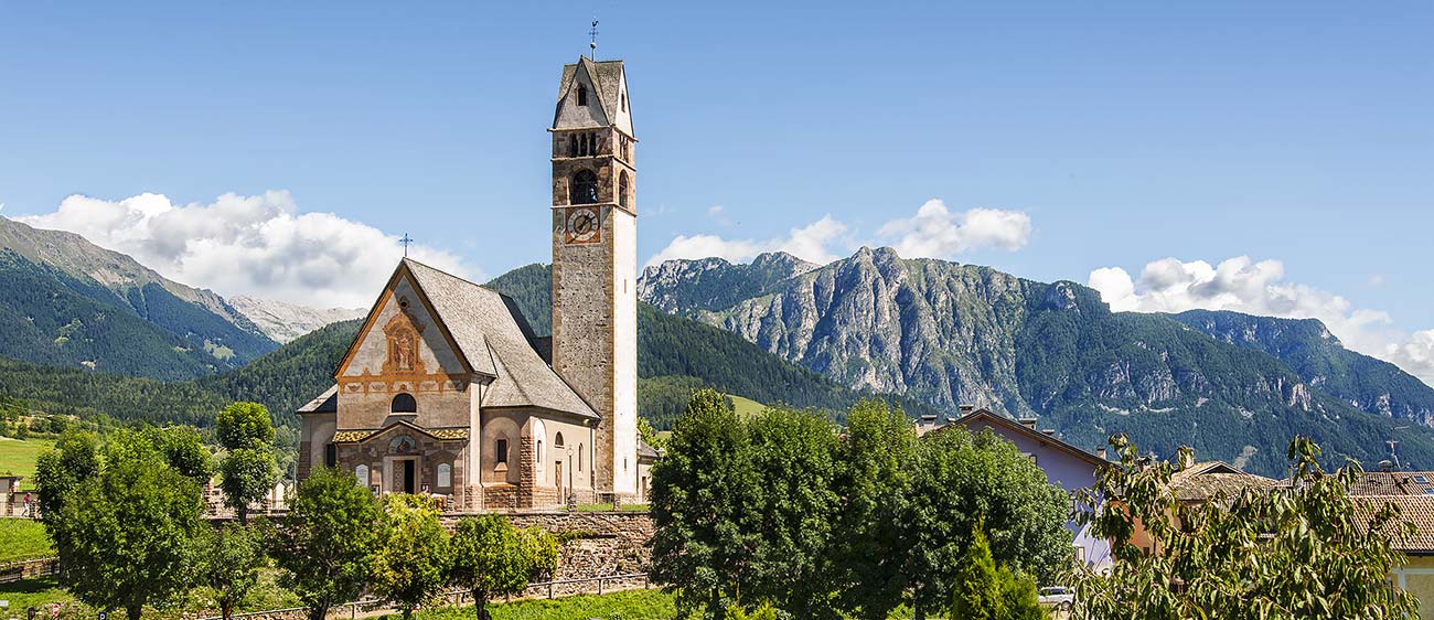 La chiesa del paese di Carano in Val di Fiemme circondata dalle montagne