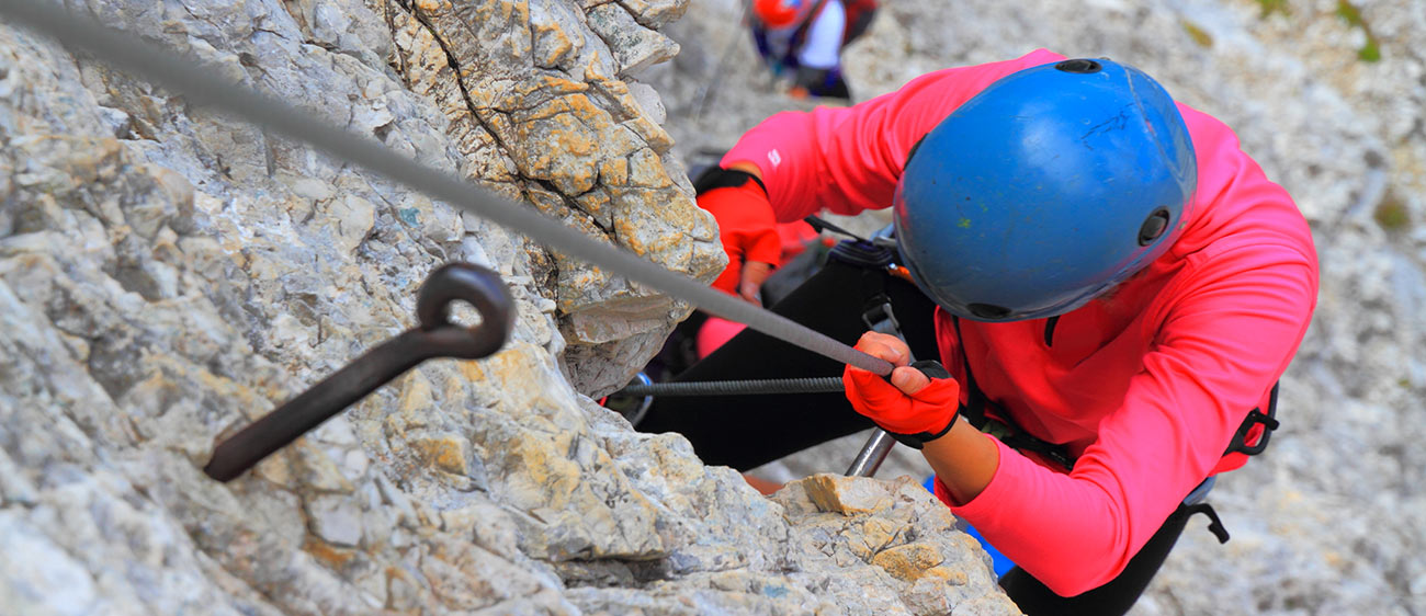 Person klettert mit professionellem Equipment eine steile Wand empor