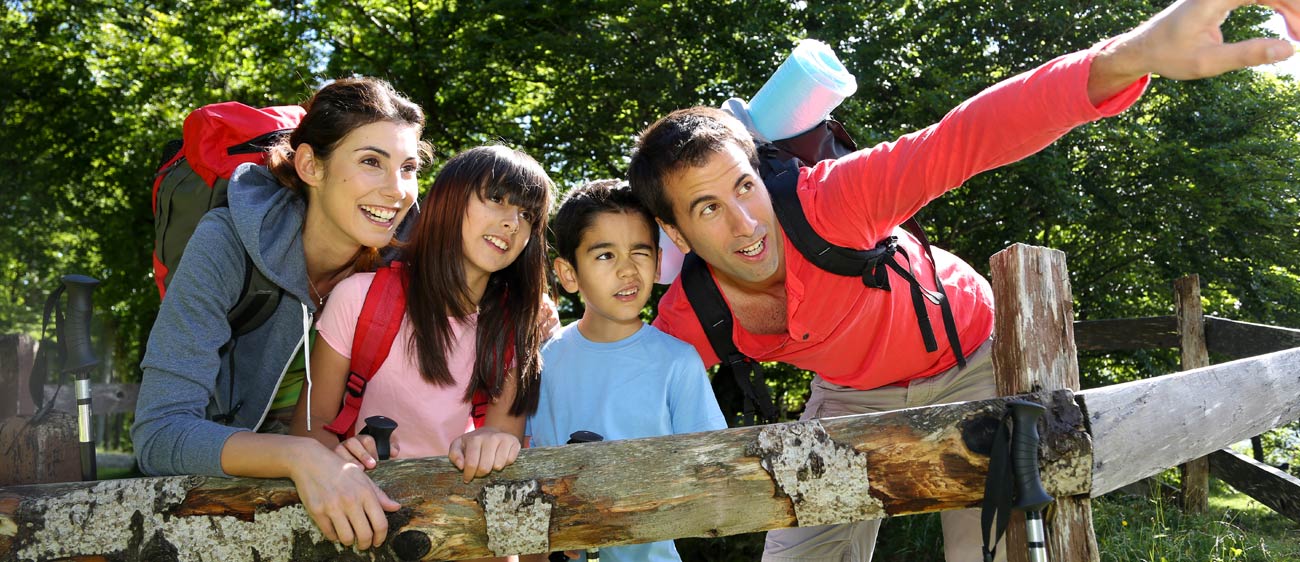 A family leaning against a fence looks into the distance