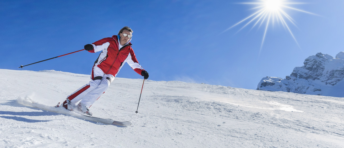Skifahrer mit weißen Hosen und roter Jacke auf der Alpe Lusia