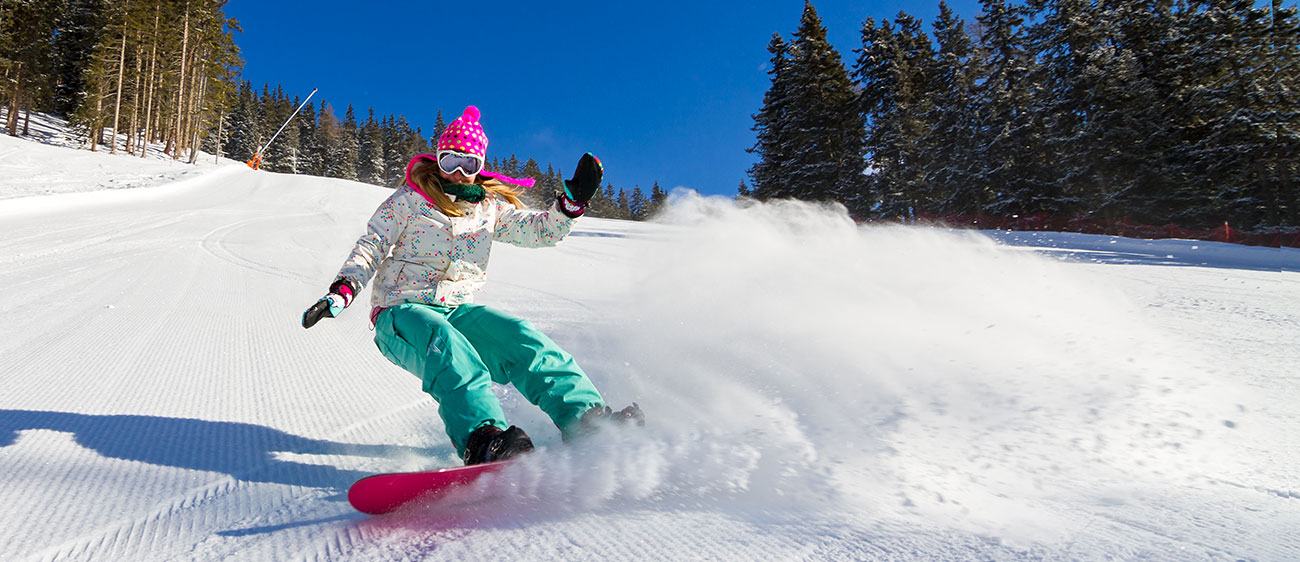 Mädchen im Skianzug beim Snowboarden