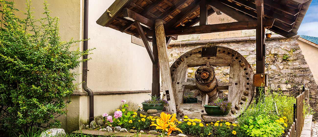 The wheel of an old wooden windmill surrounded by flowers