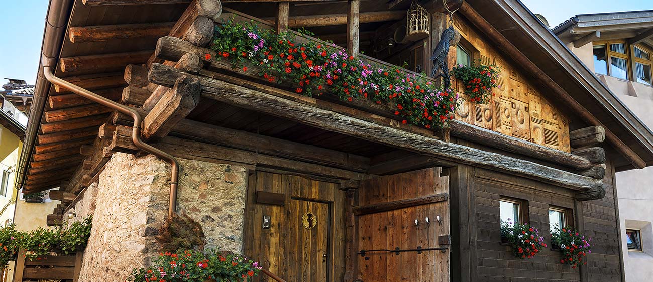 Altes Haus aus Holz und Mauerwerk mit Geranien auf dem Balkon